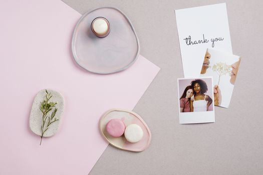Chic flat lay composition featuring macaroons, a thank you card, and decorative elements on pastel background.
