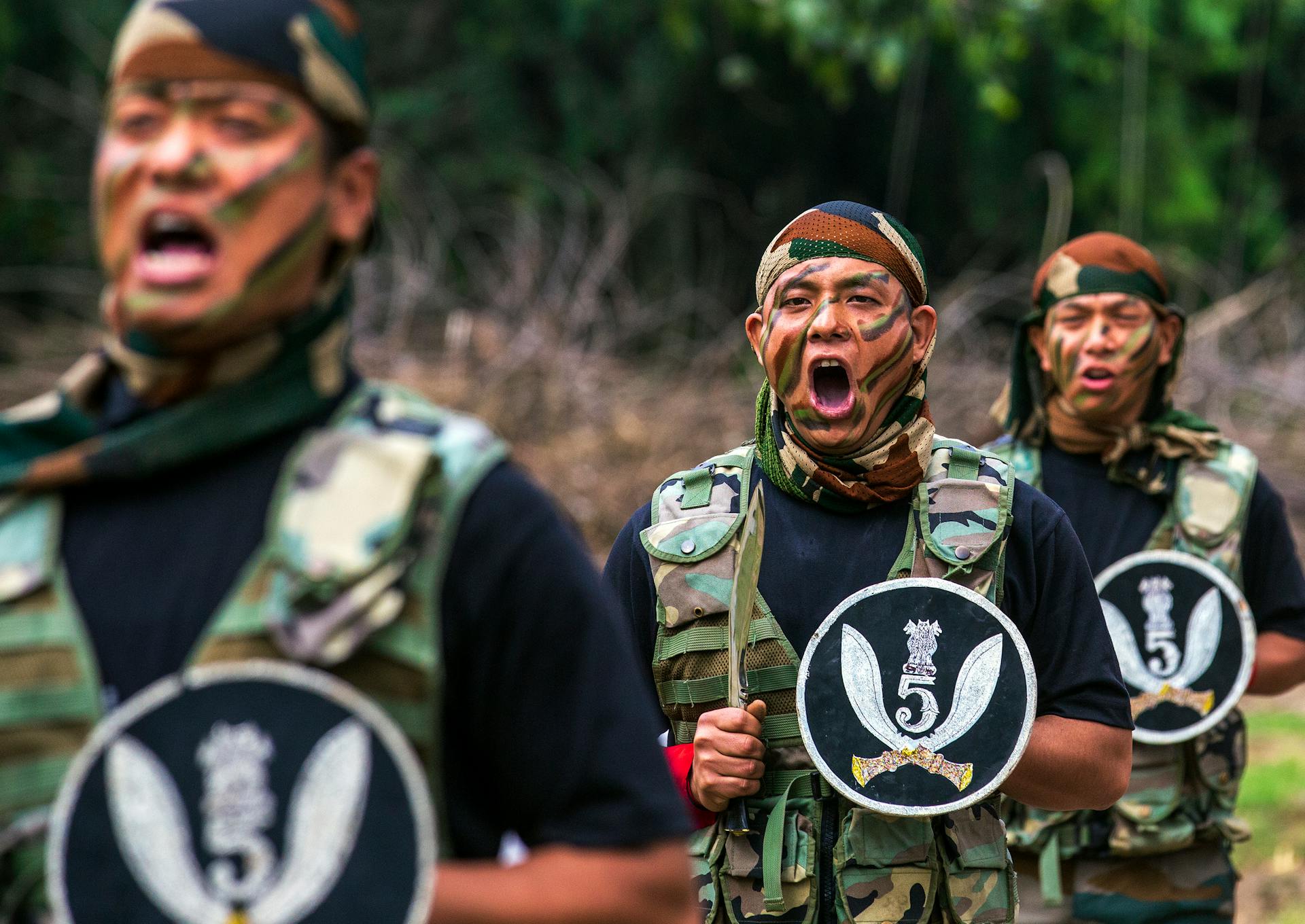 Military soldiers shouting commands in camouflage uniforms during an outdoor training drill.