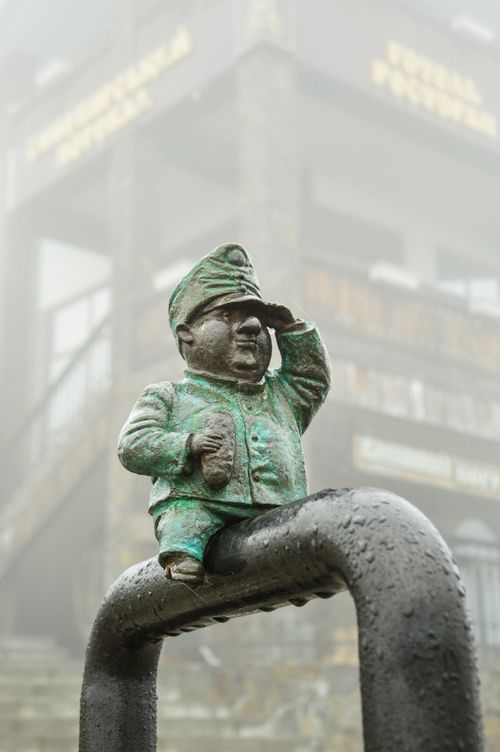 Free A bronze figurine of a soldier saluting in a foggy urban environment. Stock Photo