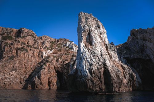 Free Vivid blue clear sky over steep bare mountains on rocky shore of dark reservoir in daylight Stock Photo