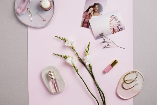 Stylish flat lay of perfume, earrings, and flowers on a pink background. Perfect for fashion and lifestyle themes.