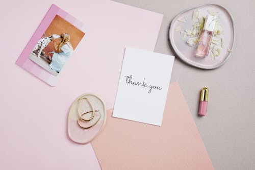 Free Thank You Card Beside a Lip Gloss and Perfume Stock Photo