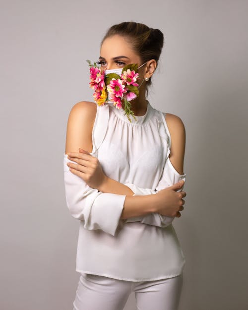 Strict female with bare shoulders and arms crossed looking away on gray background