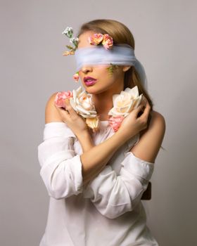 一位用玫瑰花绷带遮住眼睛的古怪、毫无感情的年轻女性，站在灰色背景前