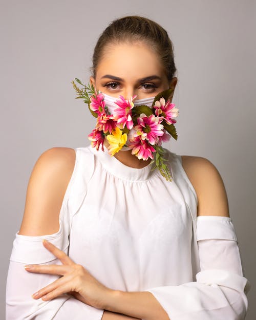 Serious haughty woman in mask with flowers