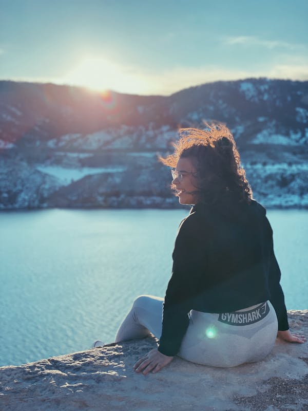 Woman Sitting Outdoors and Enjoying the View of a Lake and Mountains