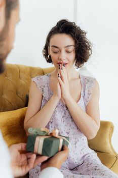 一位女士在室内高兴地收到一份包装好的礼物，惊喜与感激之情溢于言表