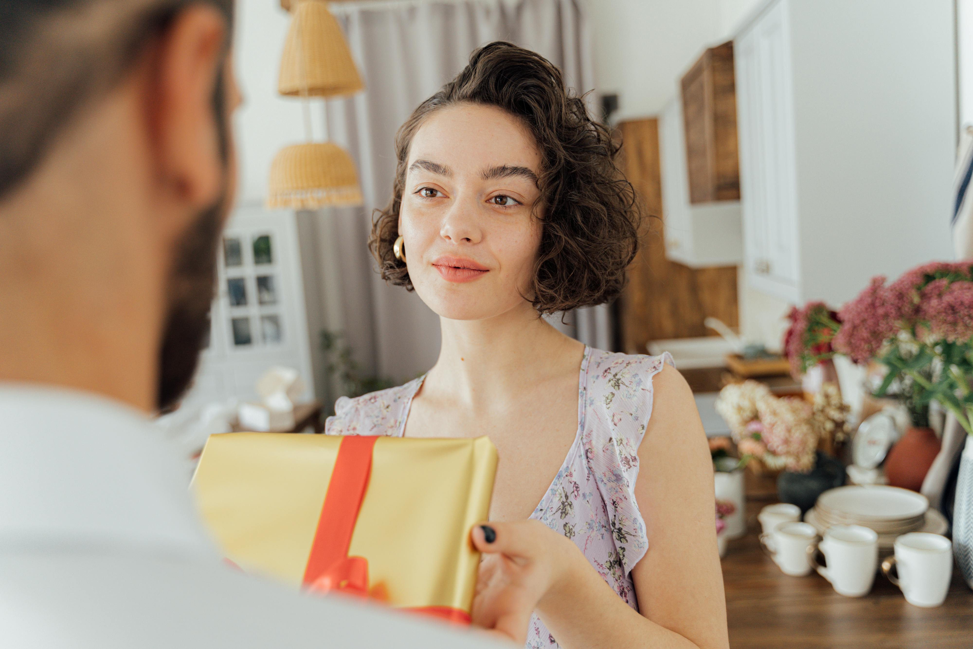 A couple sharing a heartfelt moment during a gift exchange in a warm and cozy home environment.