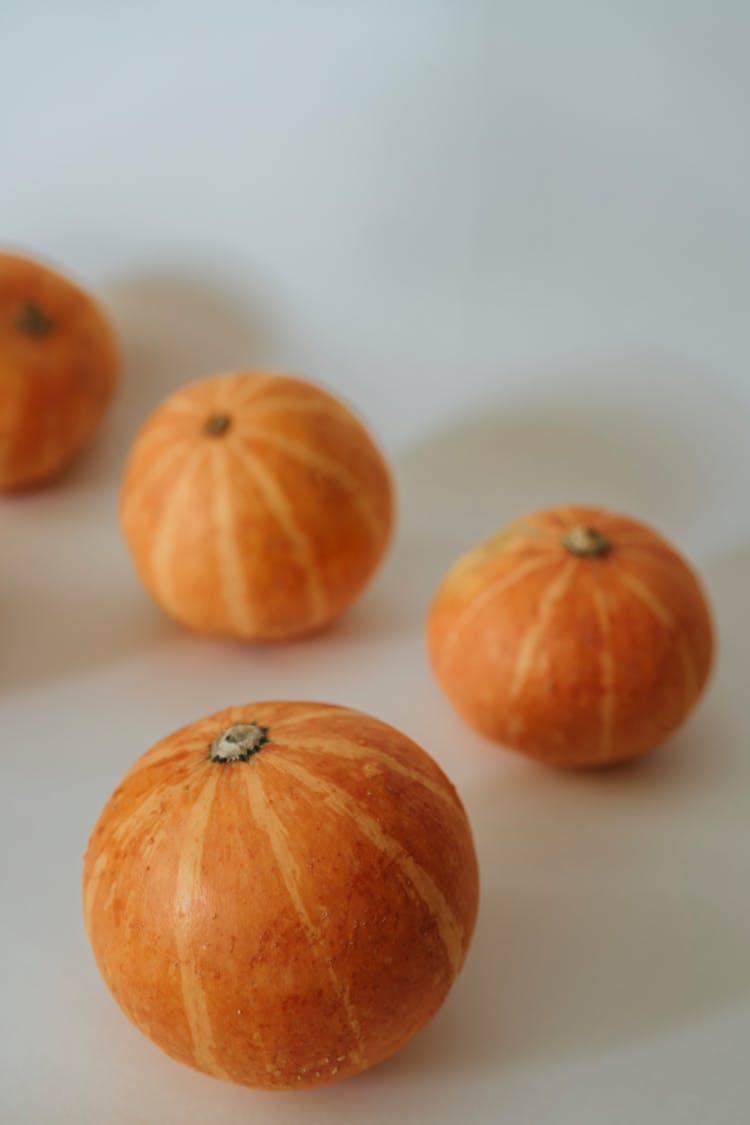 Orange Gourds On A White Surface