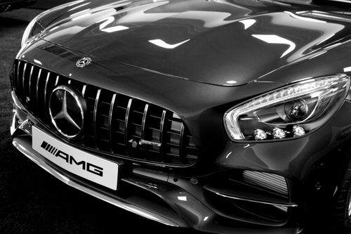 Free Detailed black and white photo of a luxury car's front grille and headlights, showcasing elegance and style. Stock Photo