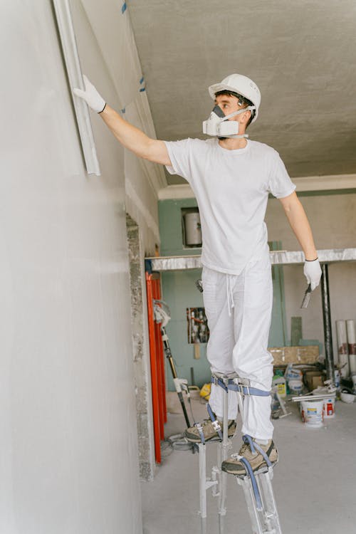 A Man Wearing White Hard Hat Renovating a House