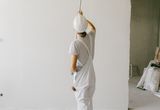 Person painting an interior wall with a paint roller