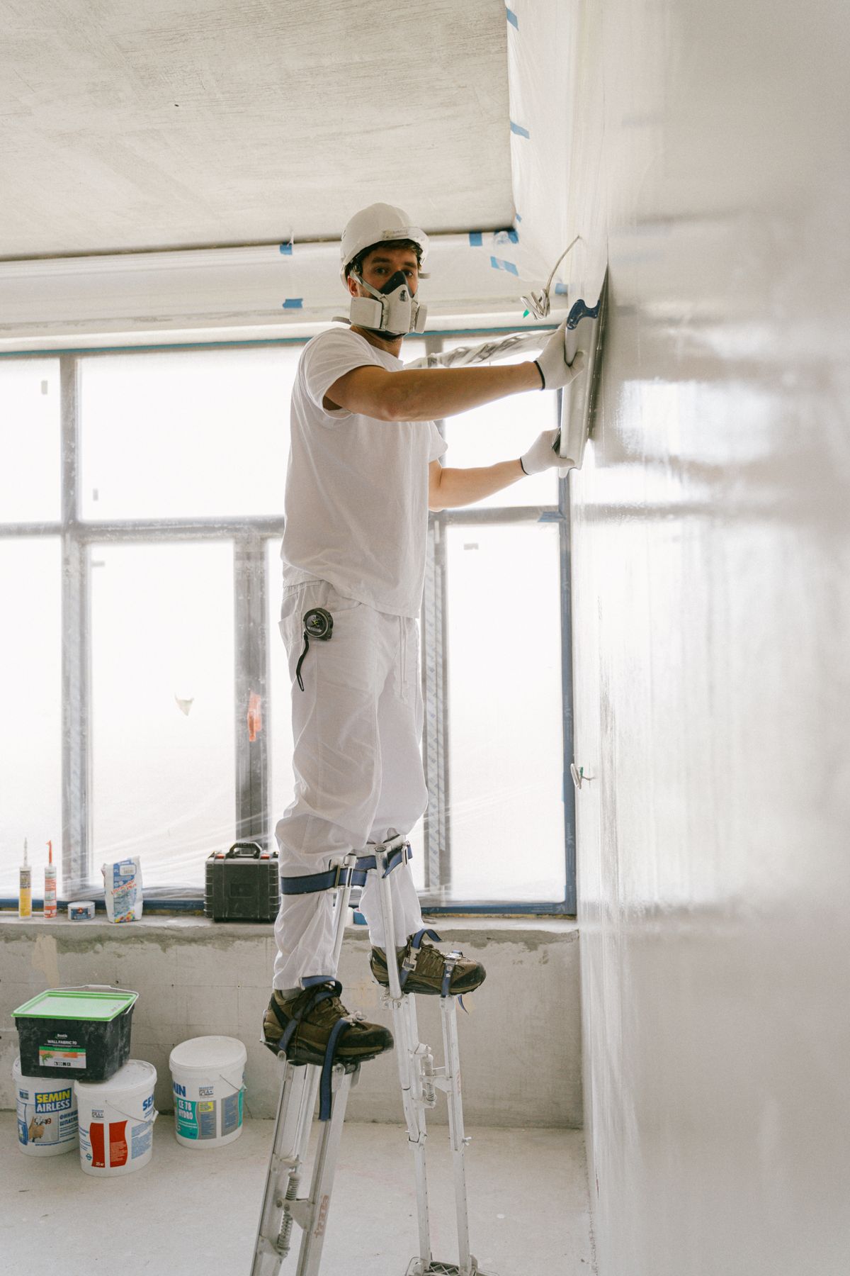 Taper smoothing joint compound on a drywall wall with a wide trowel, representative jobsite photo