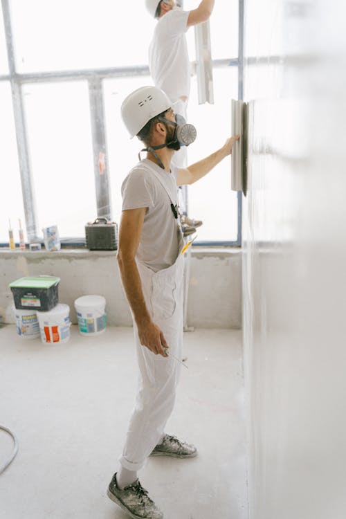  A Construction Workers Working on the Wall of a House