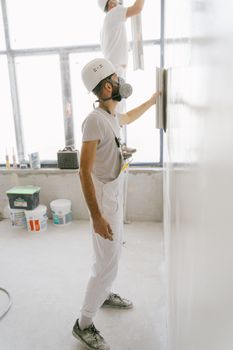 房屋装修期间，建筑工人穿着防护装备在室内粉刷墙壁