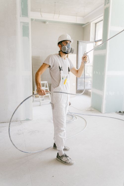 Free A construction worker in a white uniform using spray equipment inside a renovation site. Stock Photo