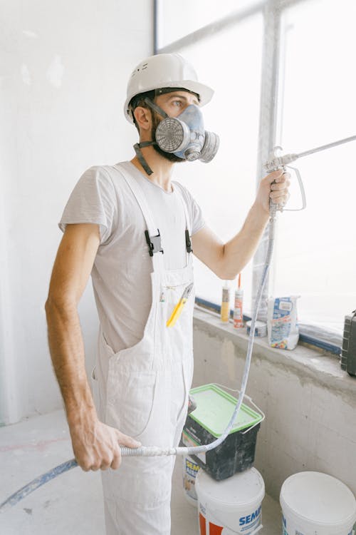 Construction Worker Holding a Hose while Working Inside a House