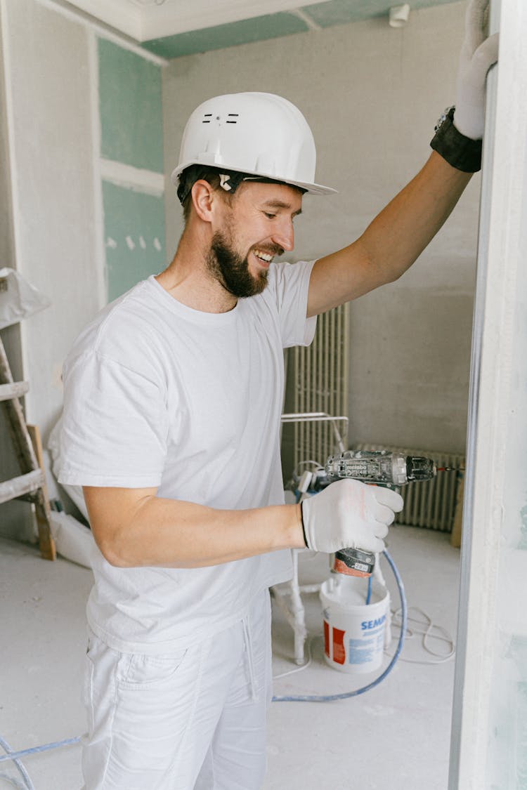 Construction Worker Painting A Wall Using A Powder Coating Tool