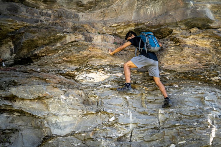 A Man In Black Shirt Climbing On The Rocky Wall