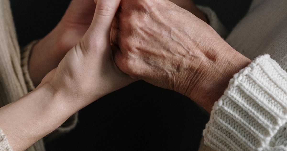 Close-up of an adult's hands gently holding an older adult's hands