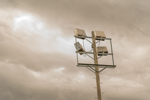 Free A vintage wooden light post stands against a cloudy sky, creating a dramatic scene. Stock Photo