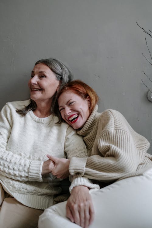 Free Mother and daughter in cozy sweaters sharing a moment of laughter, showcasing familial love. Stock Photo