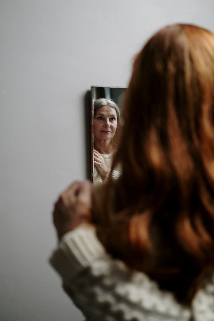 An Elderly Woman Reflection On A Mirror