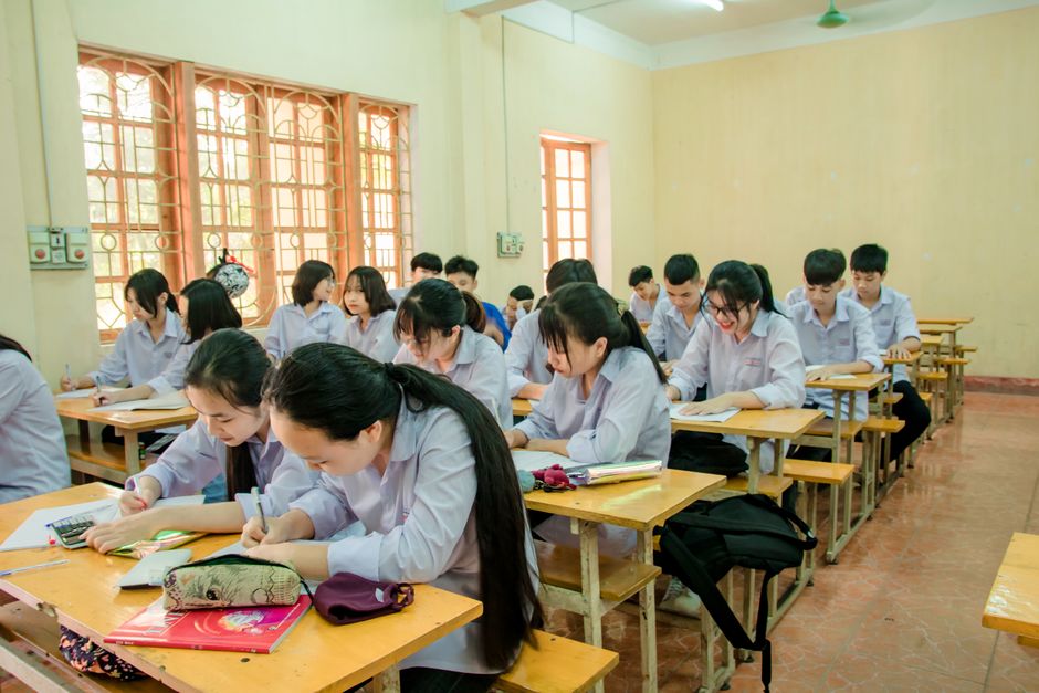 A group of students focused on studying in a brightly lit classroom environment.