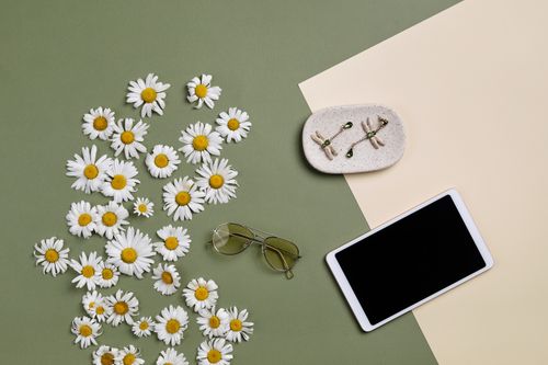 Free Chic flat lay featuring yellow daisies, sunglasses, tablet, and earrings on a two-tone background. Stock Photo