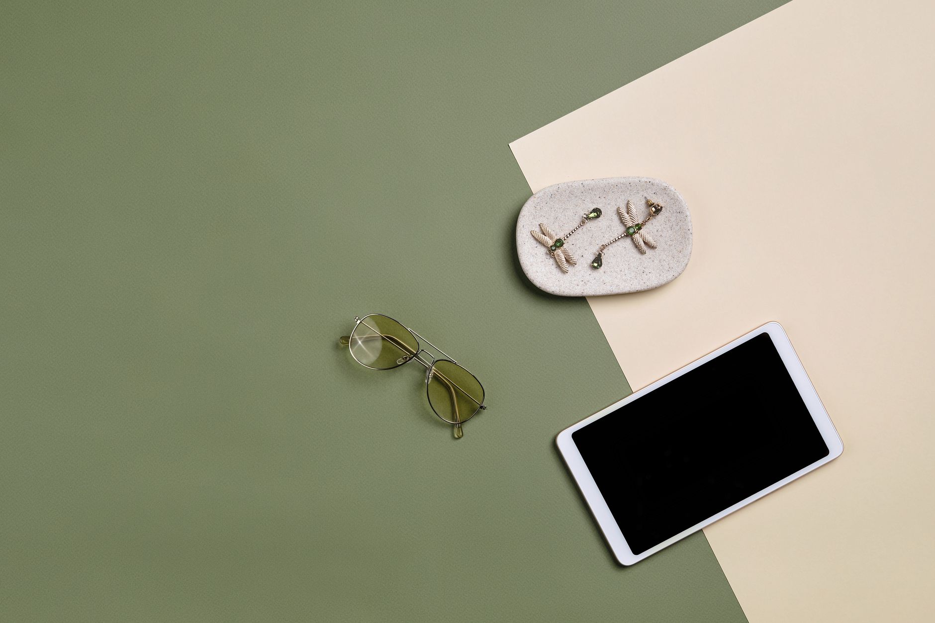 Elegant flatlay featuring sunglasses, earrings, and a tablet on a color block background.