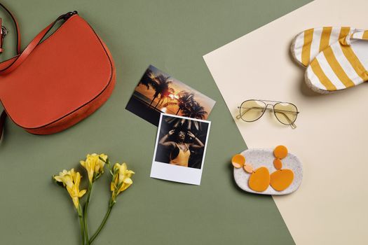 Stylish summer accessories and polaroid photos arranged on a green background.