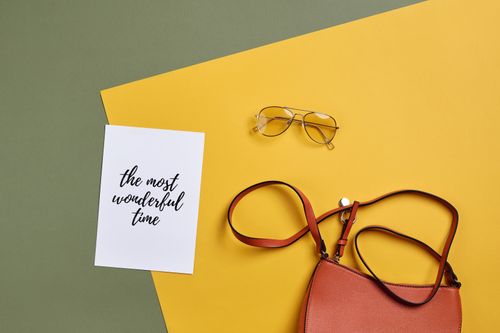 Free Flat lay featuring a handbag, sunglasses, and inspirational card on colorful background. Stock Photo