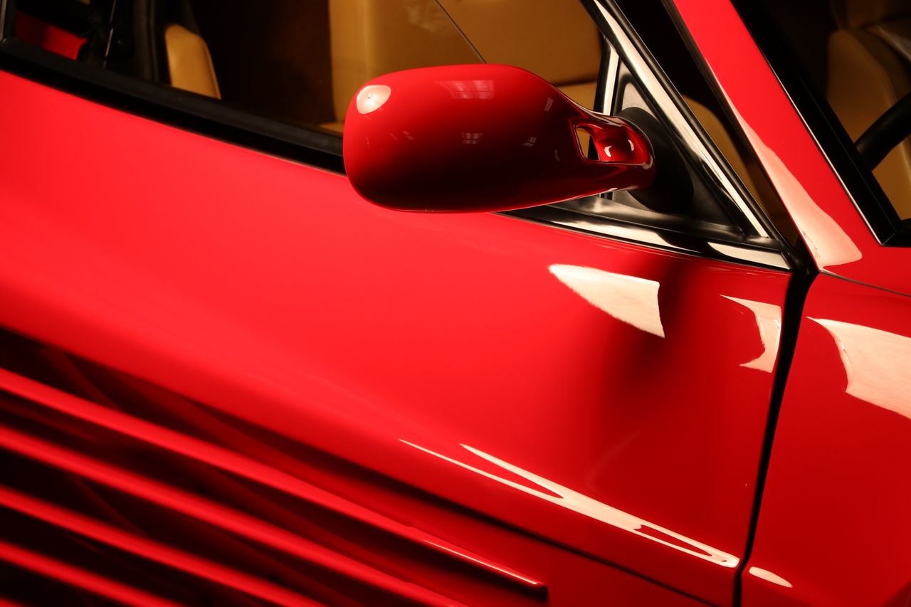 red ferrari testarossa side mirror detail shot showcasing luxury desig