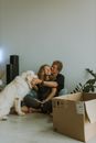 一对年轻夫妇搬家时，和一只白狗坐在纸板箱前