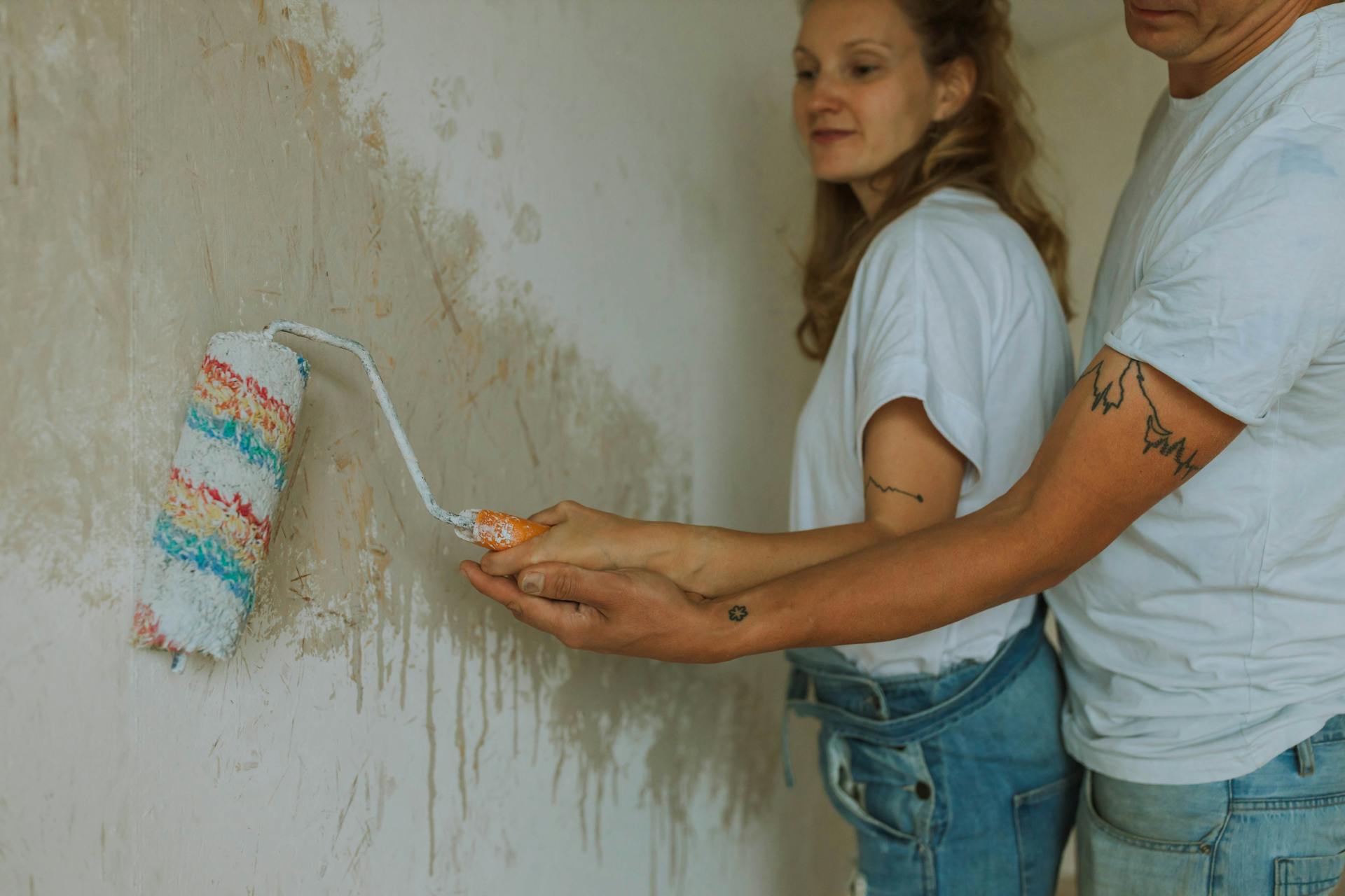 A couple painting a wall together during a home renovation project.