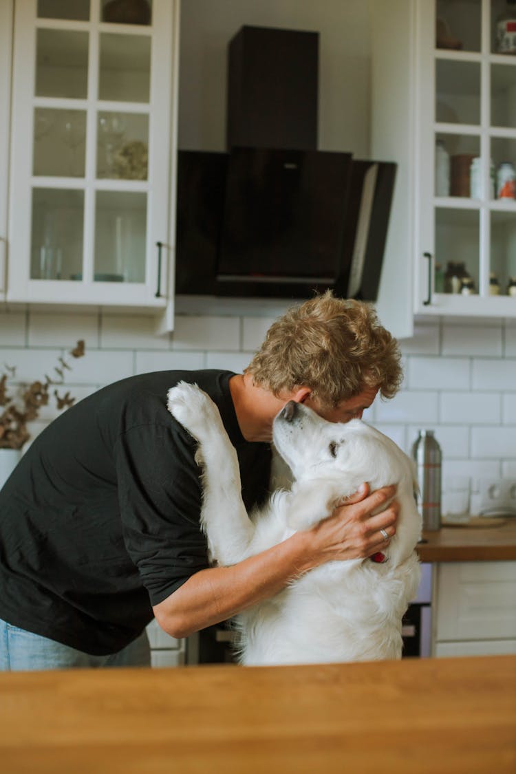 A Man Cuddling A White Dog