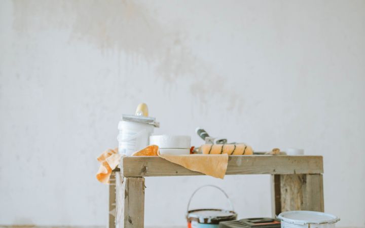 A collection of paint supplies for home renovation placed on the floor indoors, ready for wall painting.