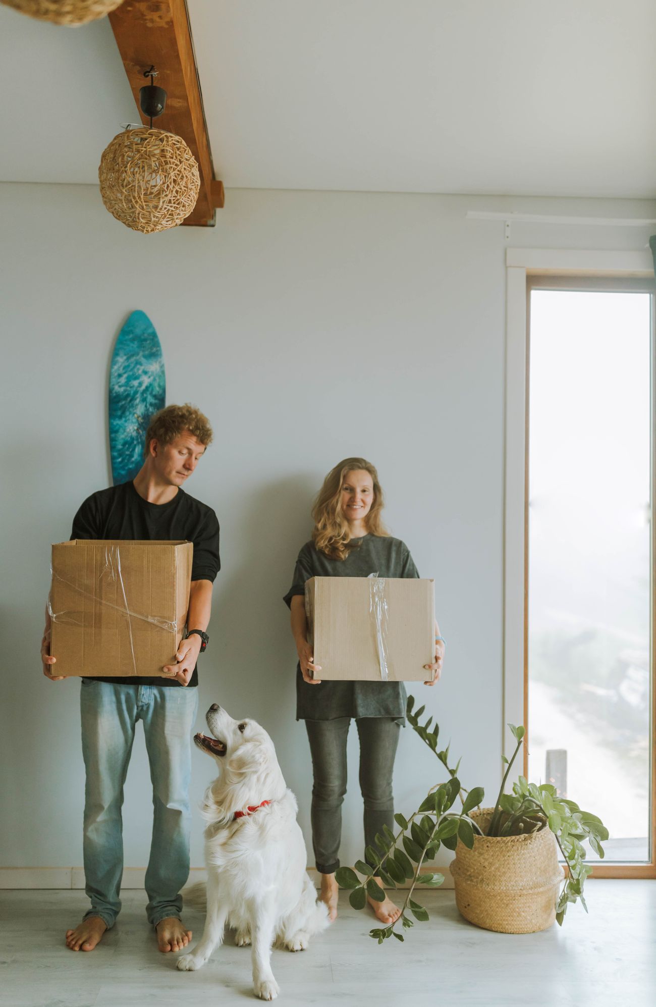 Couple with cardboard boxes and their dog in a bright welcoming home