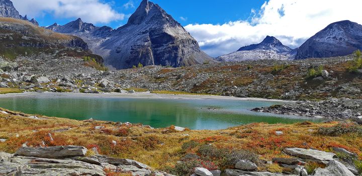 A serene mountain lake surrounded by rugged peaks and rocky landscape in Varzo, Italy.