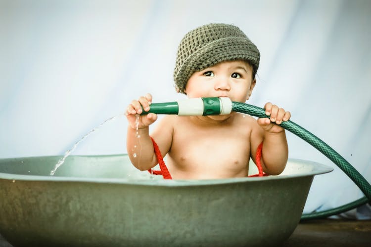 Cute Little Boy Biting Garden Hose