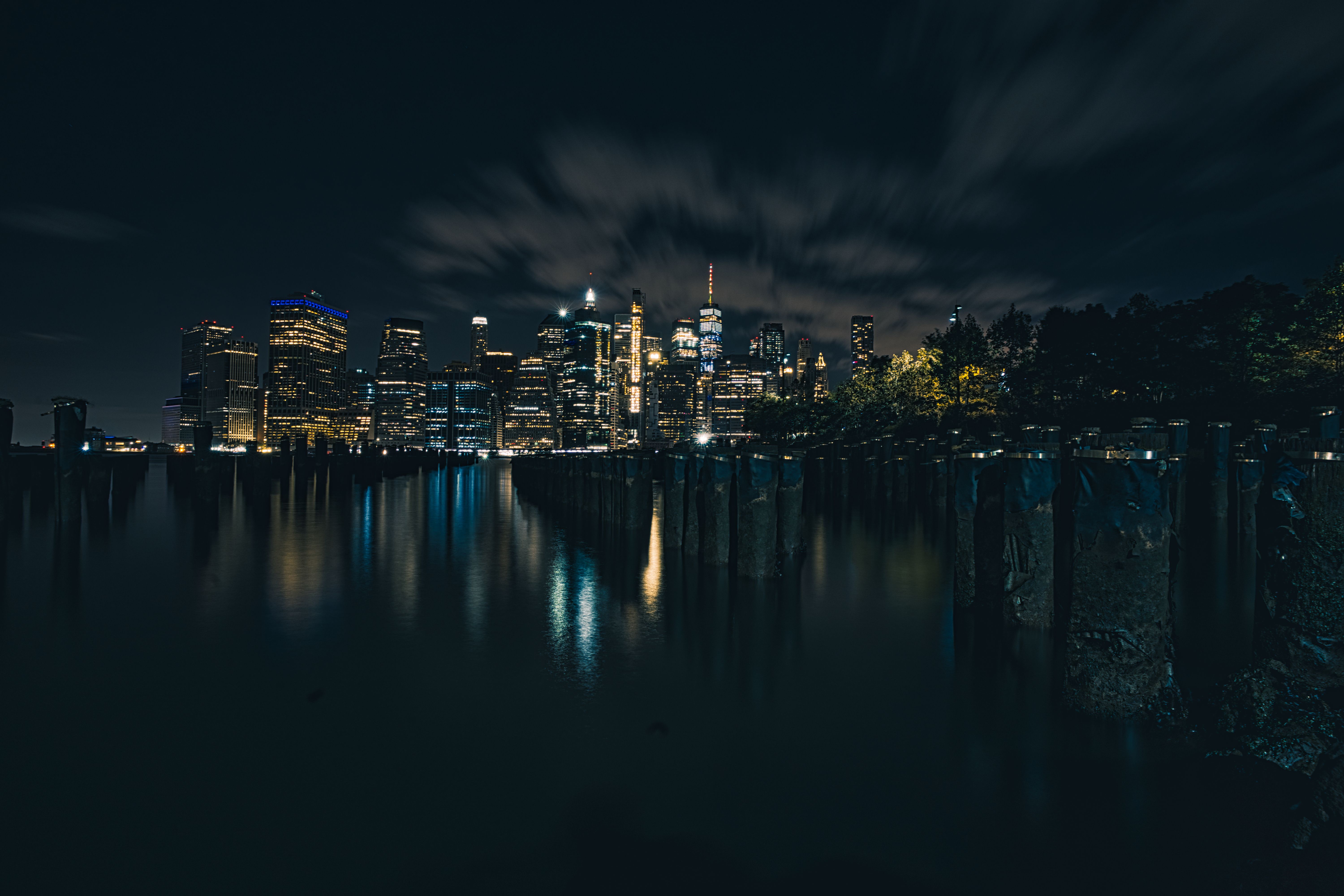 迷人的纽约市天际线在夜晚平静的水面上倒映，通过长时间曝光拍摄而成