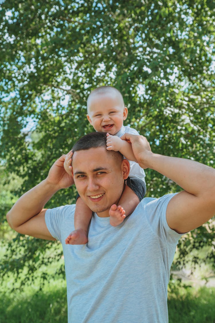 Cheerful Young Father Playing With Baby In Garden