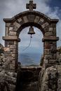 Symmetrical View of an Arch with a Bell and Landscape in Background