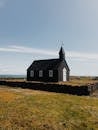 Black and White Wooden House on Green Grass Field Under White Clouds and Blue Sky during