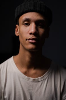 艺术工作室的肖像描绘了一位戴无檐帽的男子，背景幽暗，营造出喜怒无常的氛围