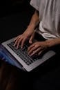 Person in White Long Sleeve Shirt Using Macbook Pro