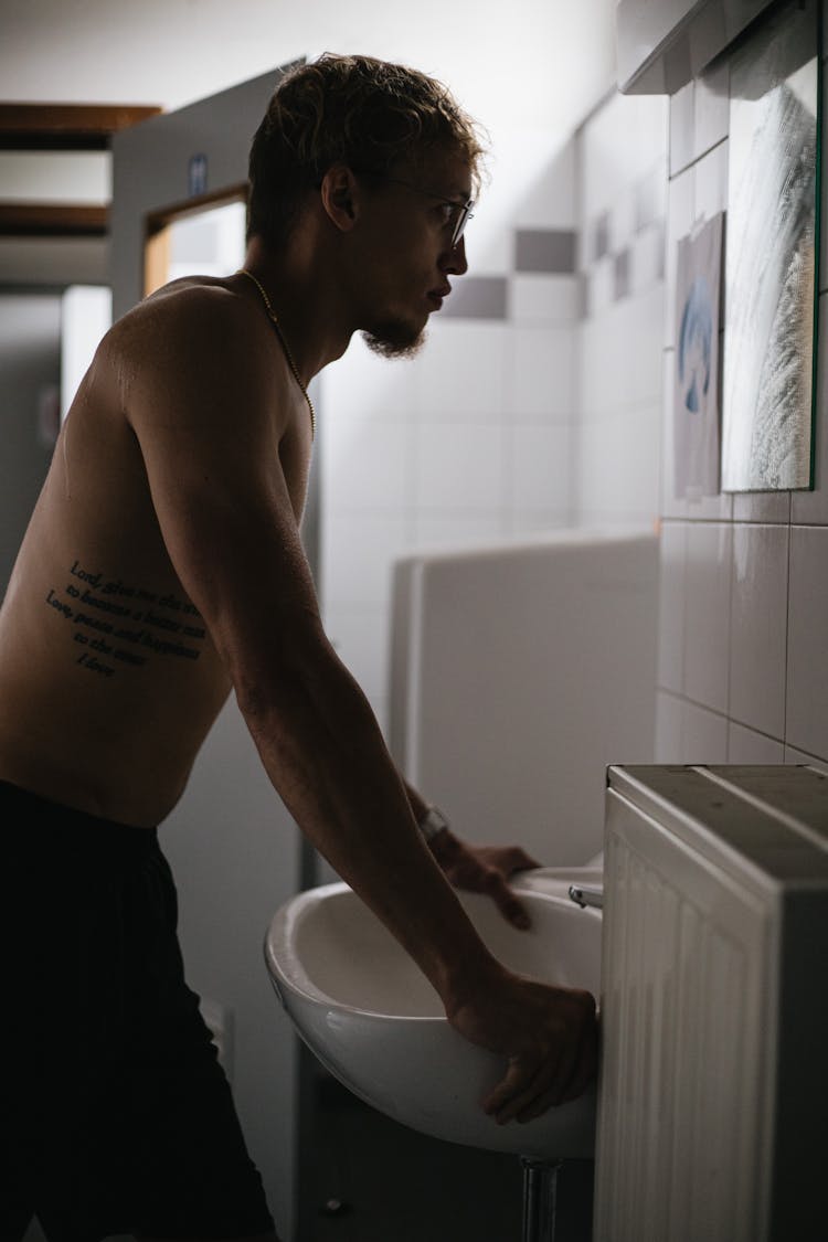 Shirtless Man Looking At Mirror In Bathroom