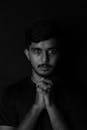 Portrait of Man with Prayer Hands on Black Background