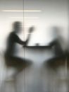 Silhouettes of People Sitting at a Table behind a Semitransparent Glass