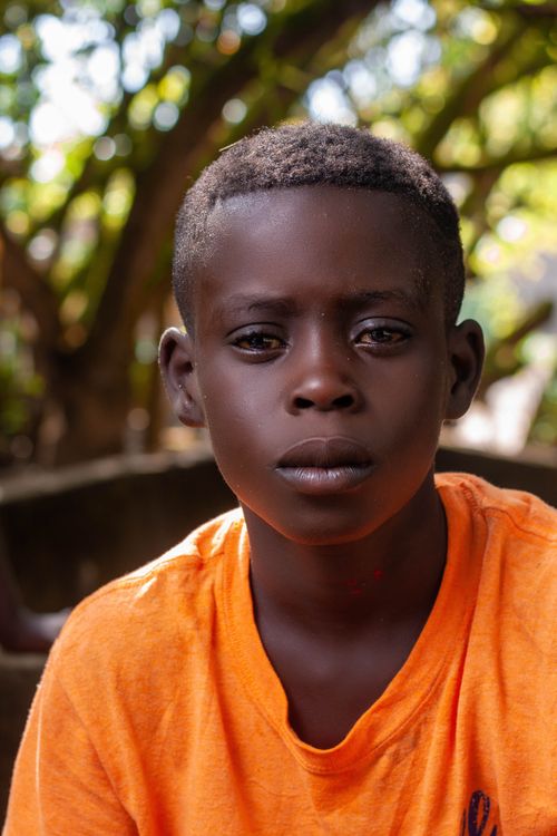 Free Close-up portrait of a young boy in an orange t-shirt with a thoughtful expression outdoors. Stock Photo